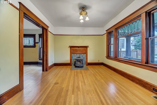 3820 N Haight Ave, Portland, OR 97227 - unfurnished living room with light wood finished floors, baseboards, a wood stove, and healthy amount of natural light