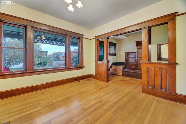 unfurnished room with light hardwood / wood-style flooring and ornate columns