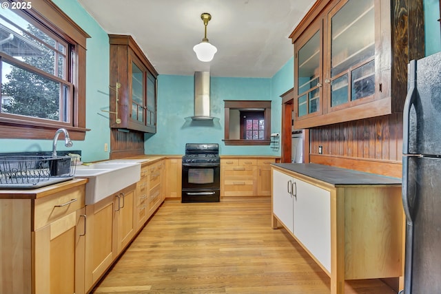 kitchen with black appliances, pendant lighting, light hardwood / wood-style floors, and wall chimney range hood