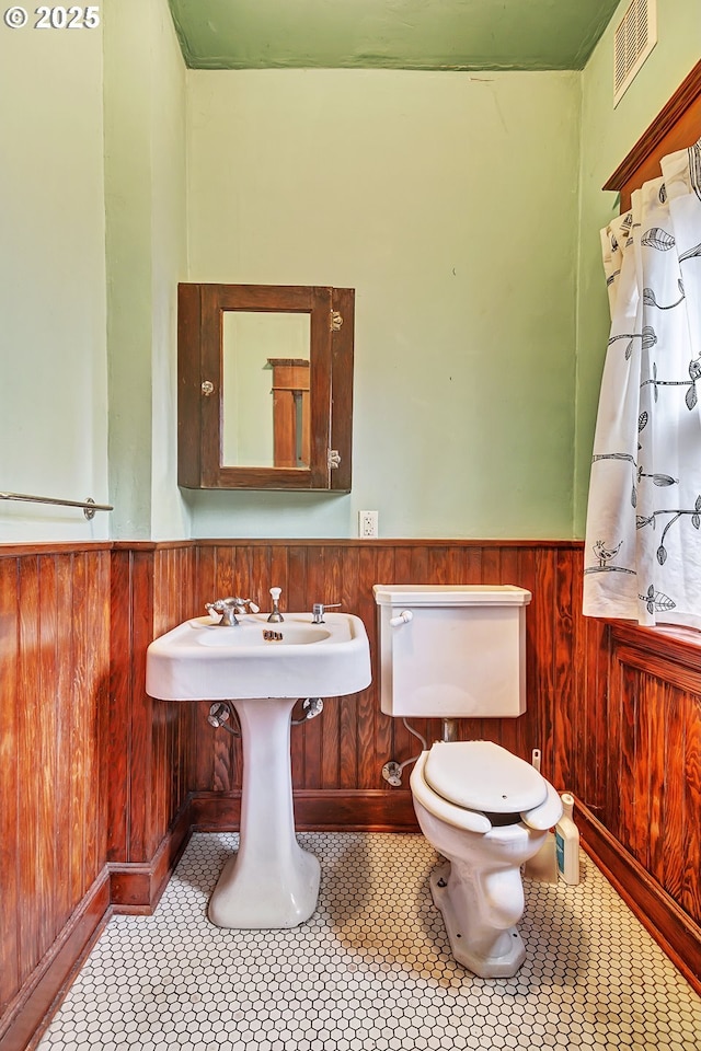 bathroom featuring toilet, wooden walls, and tile patterned floors