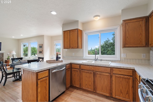 11442 SW Woodlee Heights Ct, Portland, OR 97219 - kitchen with appliances with stainless steel finishes, a textured ceiling, a peninsula, light wood finished floors, and brown cabinets