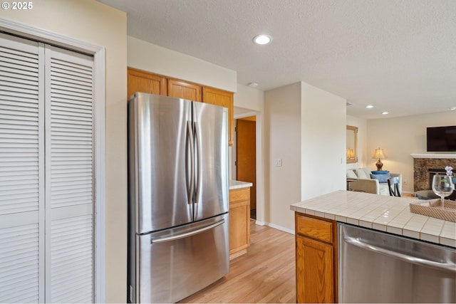 11442 SW Woodlee Heights Ct, Portland, OR 97219 - kitchen with stainless steel appliances, open floor plan, tile countertops, light wood-style floors, and recessed lighting