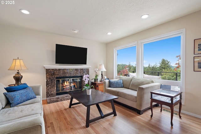 11442 SW Woodlee Heights Ct, Portland, OR 97219 - living area featuring light wood-type flooring, a high end fireplace, recessed lighting, and a textured ceiling