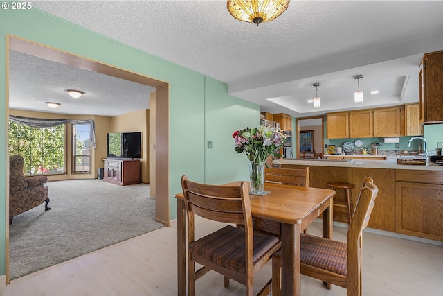3003 NE 164th St, Ridgefield, WA 98642 - dining space with a textured ceiling, a raised ceiling, light wood-style flooring, and baseboards