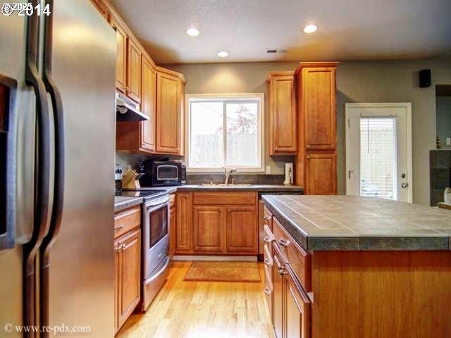 5906 NE 56th St, Vancouver, WA 98661 - kitchen featuring appliances with stainless steel finishes, under cabinet range hood, light wood-type flooring, recessed lighting, and brown cabinetry