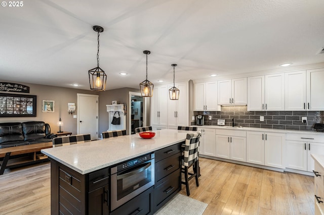 3817 NW Mccann Rd, Vancouver, WA 98685 - kitchen with white cabinetry, recessed lighting, a breakfast bar area, pendant lighting, and light wood finished floors
