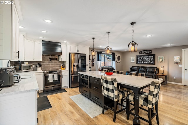 3817 NW Mccann Rd, Vancouver, WA 98685 - kitchen with stainless steel appliances, wall chimney exhaust hood, white cabinets, light wood finished floors, and recessed lighting