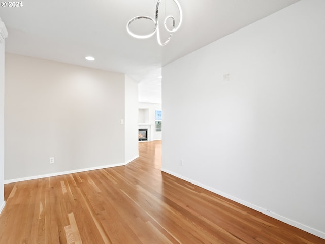 empty room featuring a notable chandelier and light wood-type flooring