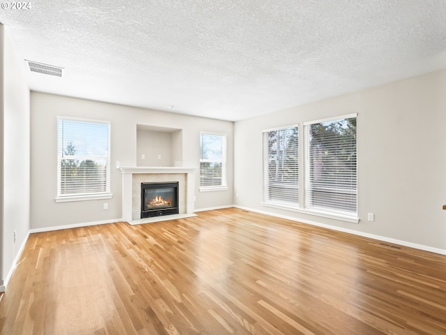 unfurnished living room featuring a healthy amount of sunlight, light hardwood / wood-style floors, and a textured ceiling