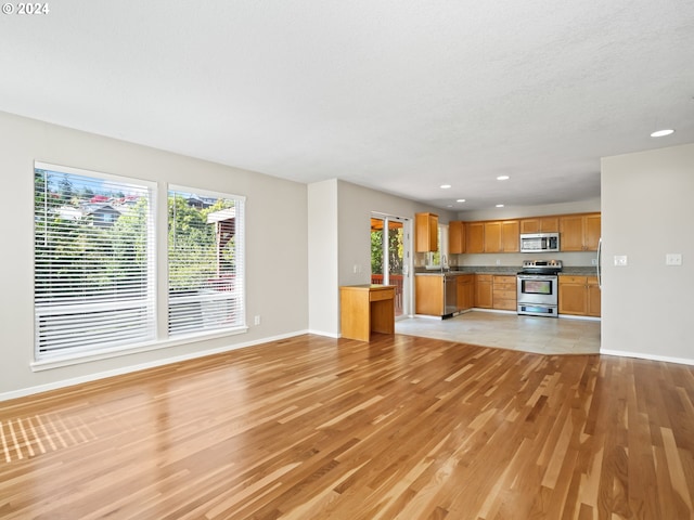 unfurnished living room with light wood-type flooring and sink