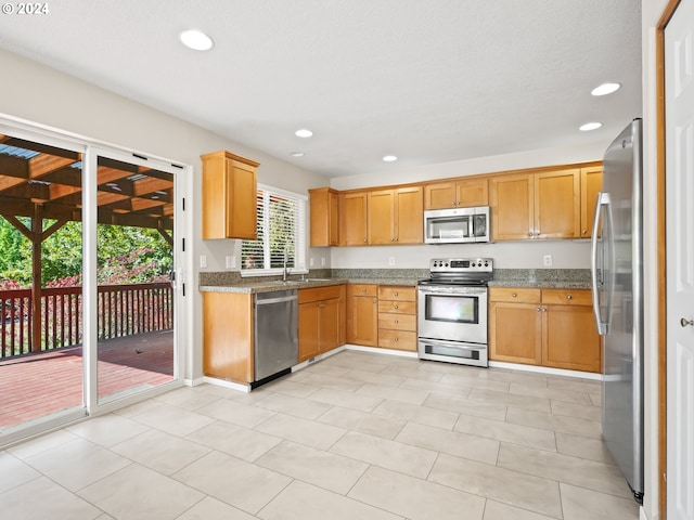 kitchen with stone counters, sink, and appliances with stainless steel finishes