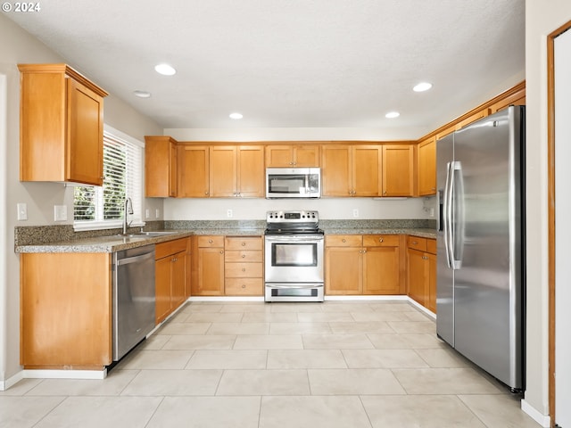 kitchen featuring stainless steel appliances, dark stone counters, and sink