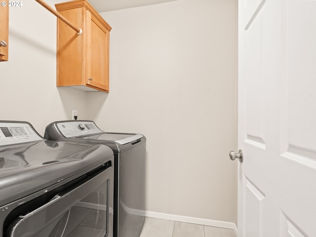 laundry room featuring cabinets, light tile patterned flooring, and washing machine and clothes dryer