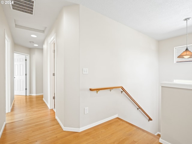 hallway with hardwood / wood-style floors and a textured ceiling