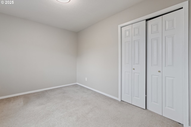 unfurnished bedroom featuring light carpet and a closet