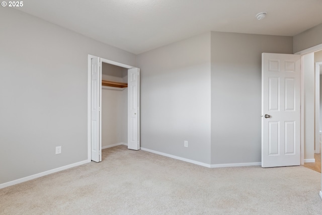 unfurnished bedroom with light colored carpet and a closet