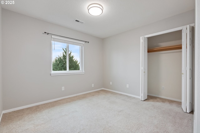 unfurnished bedroom featuring light colored carpet and a closet