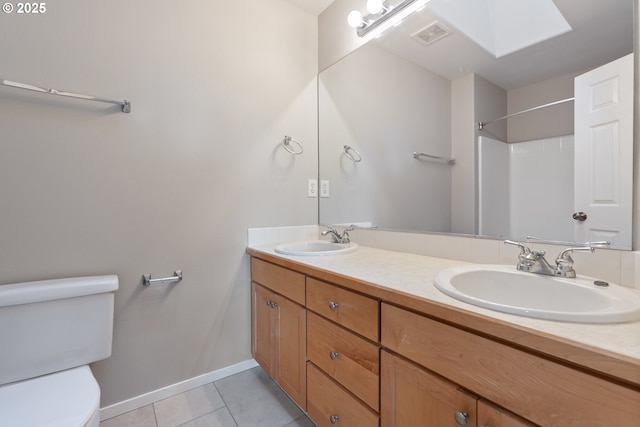 bathroom with a skylight, tile patterned flooring, vanity, and toilet