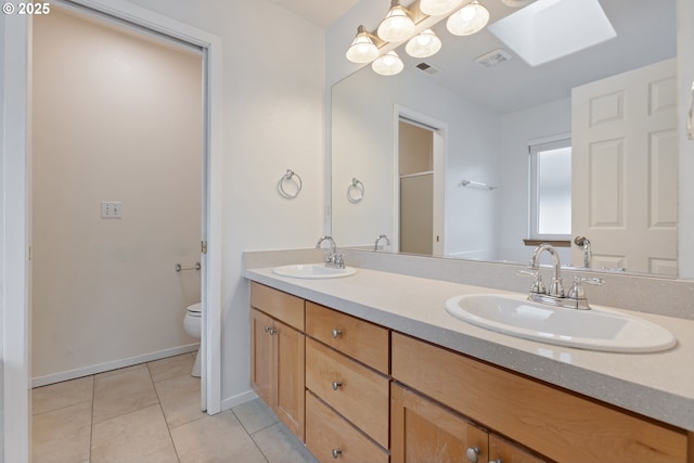 bathroom featuring tile patterned floors, a skylight, vanity, and toilet