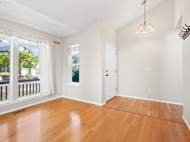 interior space featuring hardwood / wood-style flooring, vaulted ceiling, and an inviting chandelier