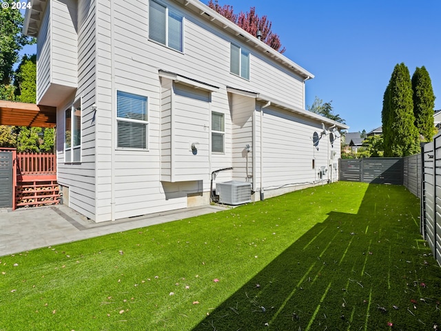 back of property with central AC unit and a yard