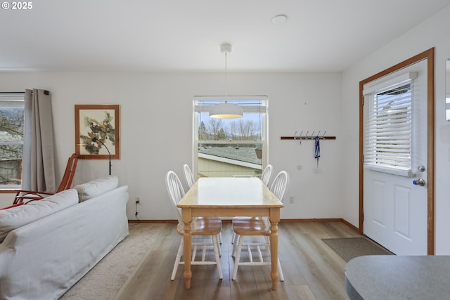 dining space with baseboards, plenty of natural light, and light wood finished floors