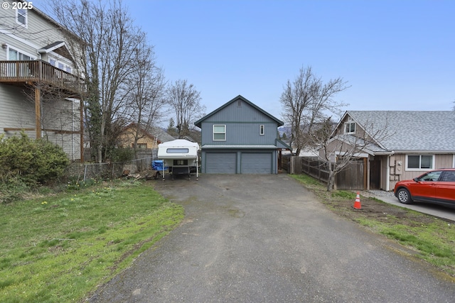 exterior space featuring a garage, a front lawn, driveway, and fence