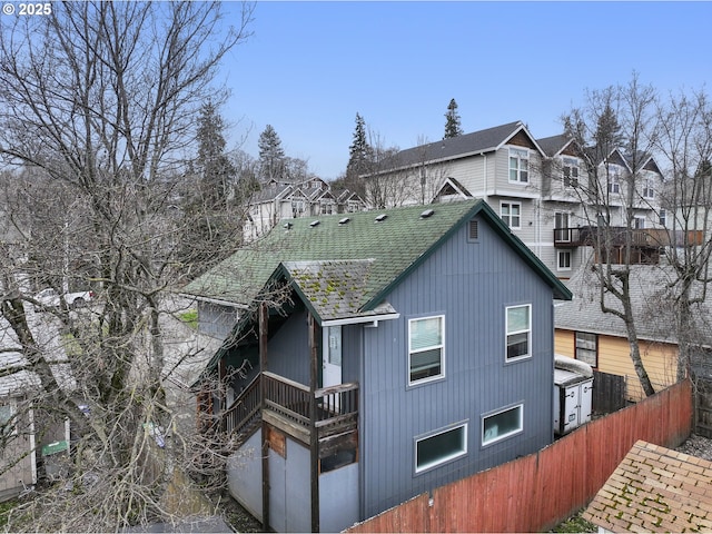 exterior space with roof with shingles and fence