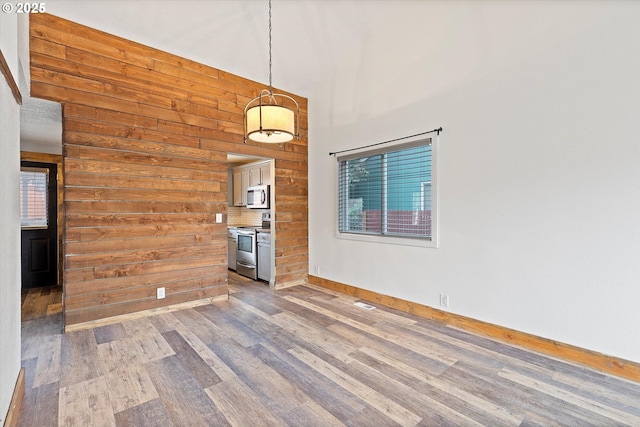 20694 SW Parker Ct, Beaverton, OR 97078 - empty room featuring wood walls, wood finished floors, healthy amount of natural light, and a high ceiling