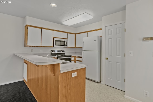 3617 Westleigh St, Eugene, OR 97405 - kitchen featuring appliances with stainless steel finishes, a peninsula, light countertops, a breakfast bar area, and white cabinets