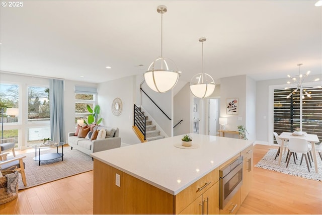 kitchen with light wood-type flooring, open floor plan, stainless steel microwave, and a center island