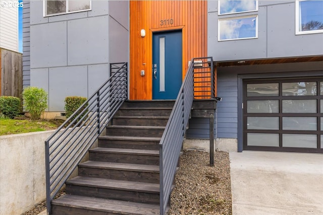 entrance to property with concrete driveway, fence, and a garage