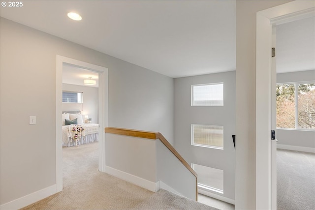 hallway featuring carpet floors, baseboards, and an upstairs landing