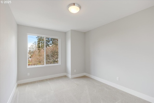 spare room featuring light colored carpet and baseboards