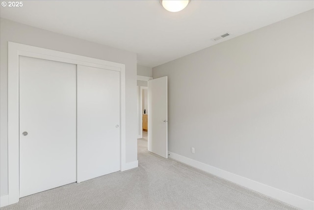 unfurnished bedroom featuring a closet, baseboards, light colored carpet, and visible vents