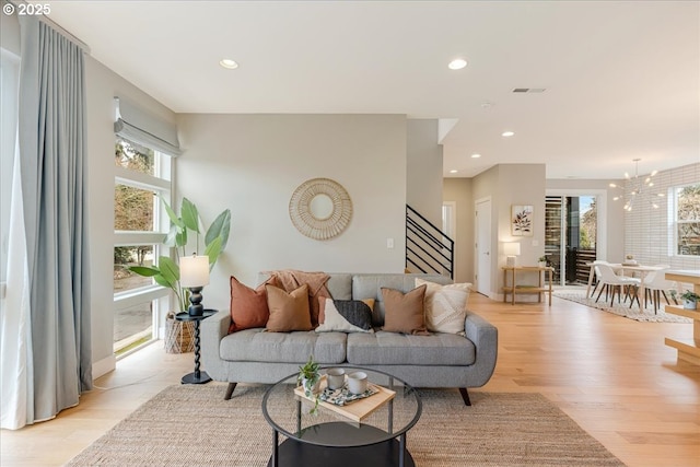 living area with stairs, plenty of natural light, and light wood finished floors