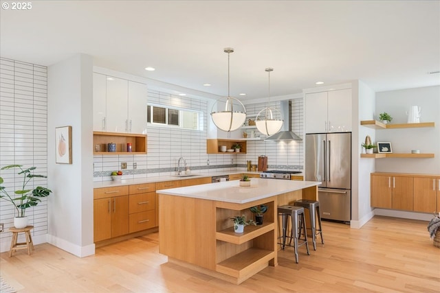 kitchen with wall chimney range hood, open shelves, stainless steel appliances, and light wood-type flooring