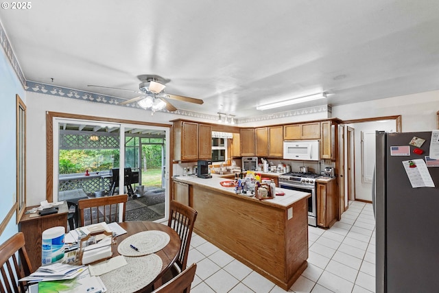 808 E 14th St, Coquille, OR 97423 - kitchen featuring stainless steel appliances, a peninsula, ceiling fan, light tile patterned floors, and light countertops