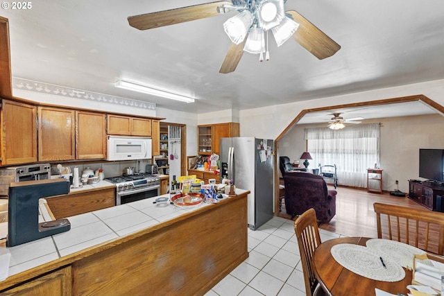808 E 14th St, Coquille, OR 97423 - kitchen featuring appliances with stainless steel finishes, tile countertops, a ceiling fan, and brown cabinetry