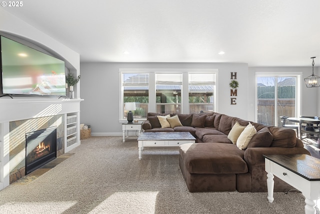 living room with a tiled fireplace, a notable chandelier, and carpet flooring