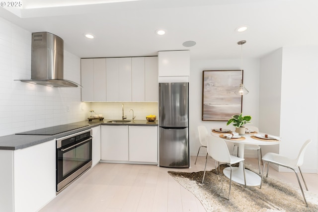 859 SW Broadway Dr Unit 41, Portland, OR 97201 - kitchen featuring dark countertops, appliances with stainless steel finishes, a sink, wall chimney exhaust hood, and white cabinetry