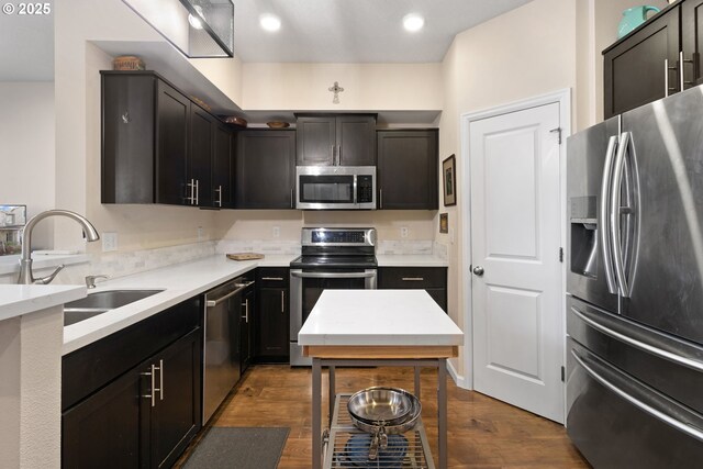 kitchen with appliances with stainless steel finishes, dark wood-style flooring, a sink, and recessed lighting