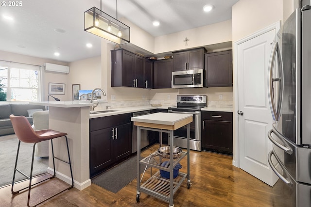 kitchen featuring dark brown cabinetry, dark wood-style floors, appliances with stainless steel finishes, an AC wall unit, and a sink