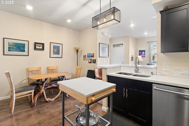 kitchen featuring light countertops, stainless steel dishwasher, a sink, and dark cabinets