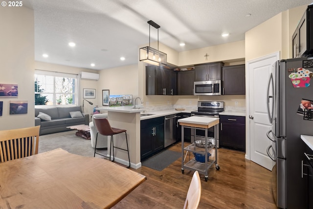 kitchen featuring a sink, open floor plan, light countertops, appliances with stainless steel finishes, and a wall mounted AC