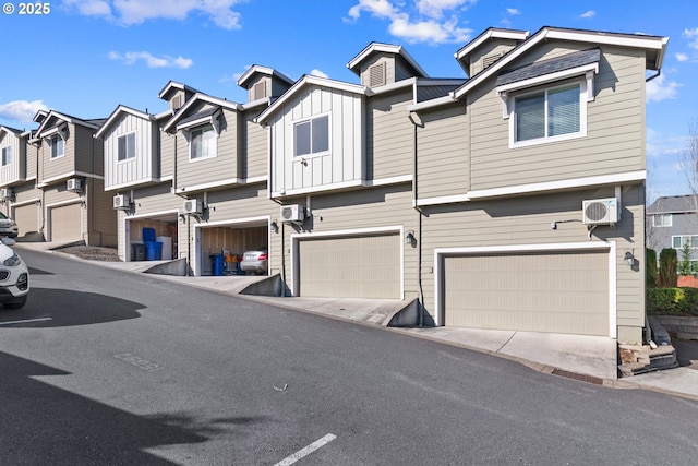 view of property featuring a garage, ac unit, board and batten siding, and a residential view