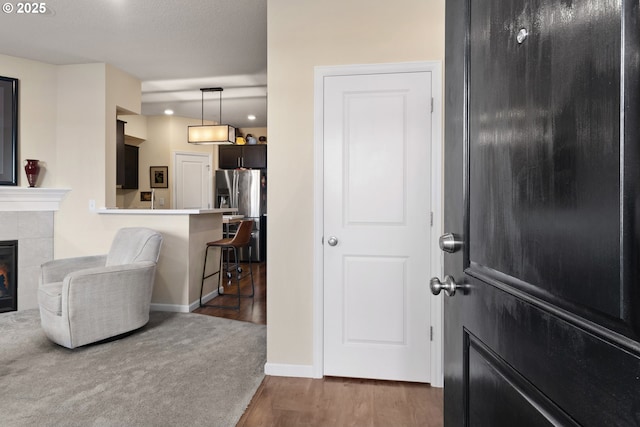 entrance foyer with carpet floors, a tiled fireplace, wood finished floors, and baseboards