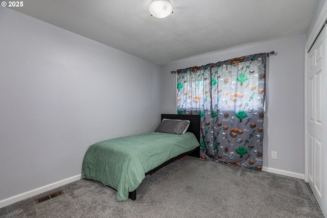 carpeted bedroom with visible vents, baseboards, and a closet