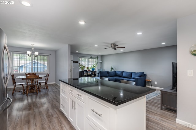 kitchen with ceiling fan with notable chandelier, freestanding refrigerator, white cabinetry, baseboards, and wood finished floors