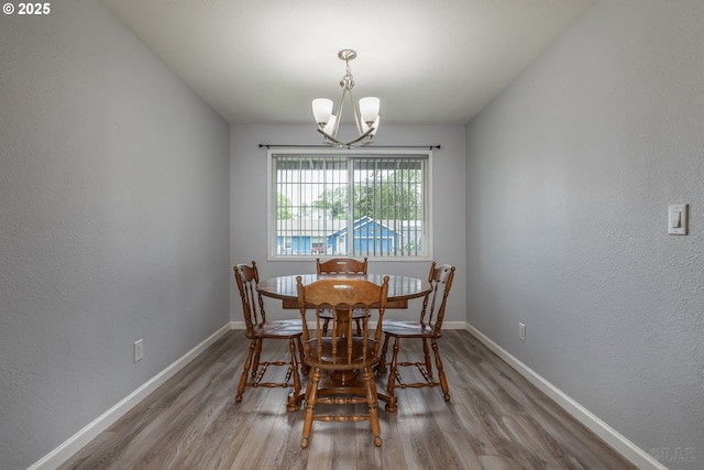 dining space with baseboards, an inviting chandelier, and wood finished floors
